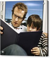 Father And Son (8-9) Reading Book On Sofa Acrylic Print