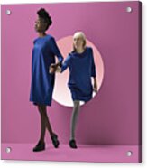 Two Women Peeking Out Of Round Opening In Coloured Wall #1 Acrylic Print
