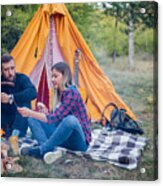 Beautiful Couple, Sitting, Camping Around The Campfire. On The Background With A Tent The Man Flicks The Fire With A Stick. #9 Acrylic Print