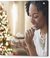 Mixed Race Woman Eating Dessert By Christmas Tree Acrylic Print