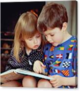 Boy(4-5)and Girl(2-3)sat By Fire In Pyjamas Reading Book Together Canvas Print