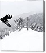 A Man On A Snowboard Flies Through The Canvas Print