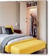 Bed With Yellow Upholstered Frame Next To Open Fitted Wardrobe Under Sloping Ceiling Canvas Print