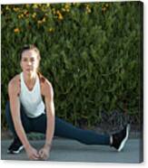 Portrait Of Confident Woman Stretching Legs Against Plants On Footpath Canvas Print