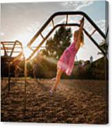 Side View Of Girl Hanging On Monkey Bars Against Sky At Playground During Sunset Canvas Print