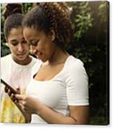Mixed-race Teenage Sisters Looking At Mobile Phone In Backyard. #2 Canvas Print