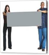 A Young Attractive Caucasian Woman And A Young African American Man Hold Up A Large Sign Together And Smile Canvas Print