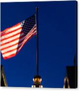 American Flag Blowing In The Wind Against A Blue Sky Canvas Print