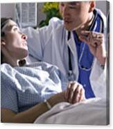 An Asian Doctor Advises A Caucasian Female As She Lies In A Bed In A Recovery Room Canvas Print