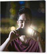 Asian Man Using His Smart Phone To Take A Photo At Night. Canvas Print