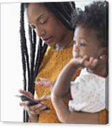 Black Woman Holding Baby Daughter Using Cell Phone Canvas Print