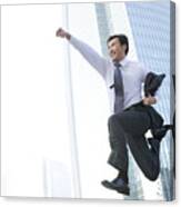 Businessman Jumping In Front Of Tall Building Canvas Print