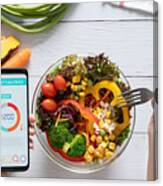 Calories Counting , Diet , Food Control And Weight Loss Concept. Calorie Counter Application On Smartphone Screen At Dining Table With Salad, Fruit Juice, Bread And Fresh Vegetable. Healthy Eating Canvas Print