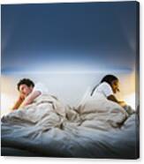 Couple ignoring each other on bed Canvas Print