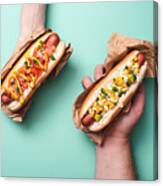 Cropped View Of Man And Woman Holding Two Tasty Hot Dogs In Paper On Blue Canvas Print