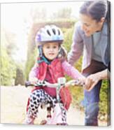 Mother Is Teaching Her Daughter Cycling. Canvas Print