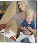 Mother Working And Holding Son On Lap Canvas Print