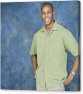Portrait Of A Young African American Man In A Green Shirt And Tan Pants Puts His Hands On His Hips And Smiles Canvas Print