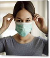 Portrait of young woman putting on a protective mask Canvas Print
