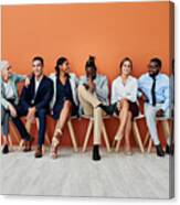 Shot Of A Group Of Businesspeople Sitting Against An Orange Background Canvas Print
