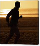 Silhouette Of A Tall Man Running On Beach At Sunset Stock Photo Canvas Print