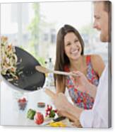 Woman Watching Husband Flipping Stirfry In The Kitchen Canvas Print