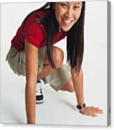 Young Woman With Long Hair Wears Red T-shirt And Shorts Crouches Her Hands On Floor Smiles To Camera Canvas Print