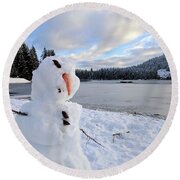 Closeup shot of a deformed snowman with a frozen lake in the