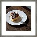 A Cinnamon Roll On A Plate With A Bite Framed Print