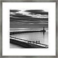 A Curving Pier With A Lighthouse At The Framed Print