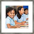 Cute Schoolgirl Smiles At The Camera In Classroom Framed Print