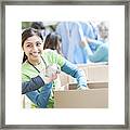 Male And Female Volunteers Sort Donations During Food Drive Framed Print