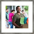 Man Holding Box Of Clothes Donations At A Donation Center Framed Print
