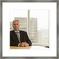 Mature Businessman Sitting At Desk, Smiling, Portrait Framed Print