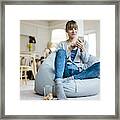 Smiling Woman Sitting In Beanbag Using Cell Phone Framed Print