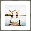 Two Friends Jumping Off Jetty At Lake Together Framed Print