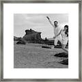 Couple Leaping Off Of Rock Framed Print