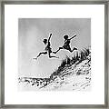 Two Girls Leaping Off Sand Dune Framed Print