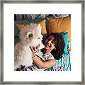 A Little Girl Is Playing With Her White Pomeranian Puppy In Bed. Framed Print
