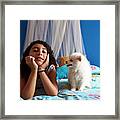 A White Pomeranian Puppy Looks At Its Owner While Sitting On The Bed Framed Print