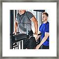 Gym Instructor Helping Senior Man At The Gym. Framed Print