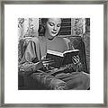 Young Woman Sitting On Sofa, Reading Framed Print