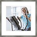 Happy Caucasian Woman On Elliptical Trainer At Gym Framed Print