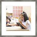 Mixed Race Down Syndrome Student Using Tablet Computer In Classroom Framed Print