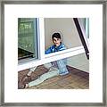 Portrait Of A Young Man Sitting At A Wall And Looking Outside Through Window Framed Print