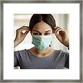 Portrait Of Young Woman Putting On A Protective Mask Framed Print