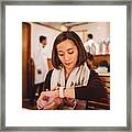 Pretty Young Lady Waiting And Using Her Smartwatch Joyfully In The Restaurant Framed Print