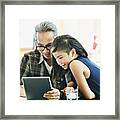 Smiling Girl And Father Making Video Call On Digital Tablet While Sitting In Dining Room Framed Print