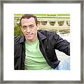 Smiling Handsome Young Man Sits In Front Of A Reflection Pond. Framed Print