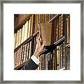 Woman Reaching For Book In Library Framed Print